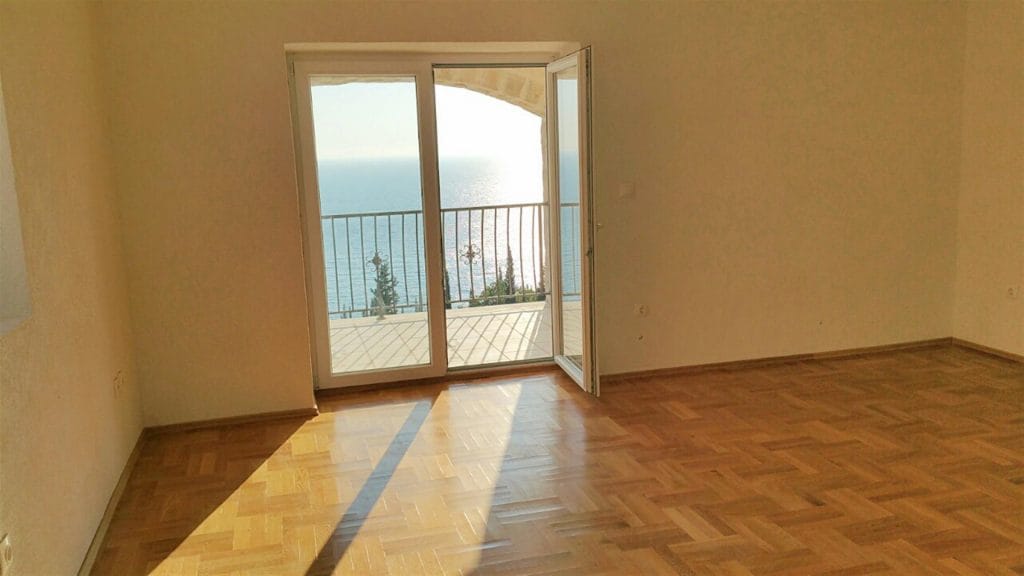 Living room with parquet flooring and access to a balcony with panoramic sea views in a villa, Drobni Pijesak, Montenegro.