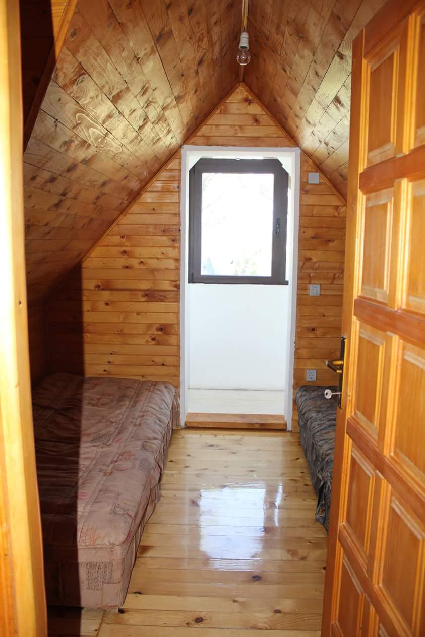 Bedroom in the attic of a house in Sutomore, Montenegro: wooden wall paneling, two beds, and access to the balcony.