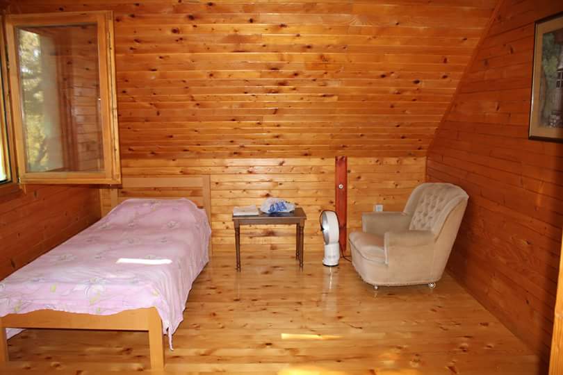 Bedroom in a wooden house in Sutomore, Montenegro: single bed, armchair, and tongue-and-groove paneling in the attic.