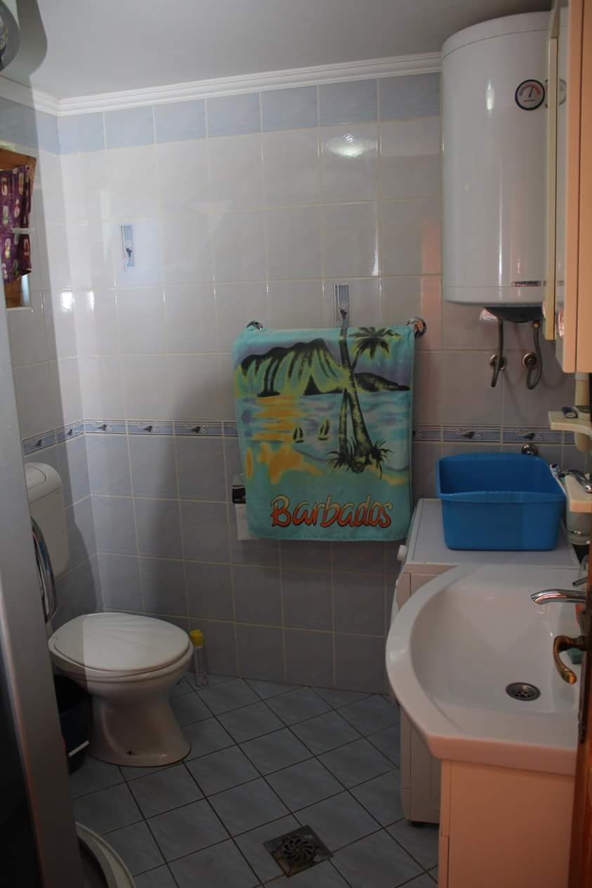 Bathroom in a house in Sutomore, Montenegro: light tiles, plumbing fixtures, a water heater, and a washing machine in the interior.