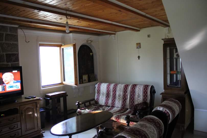Living room in a house in Sutomore, Montenegro: wooden ceiling, upholstered furniture, display cabinet, and TV in the interior.