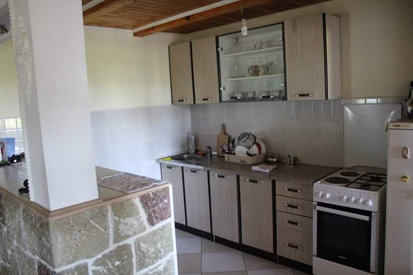 Kitchen in a house in Sutomore, Montenegro: light-colored cabinets, stove, stone finish on the bar counter, and a wooden ceiling.