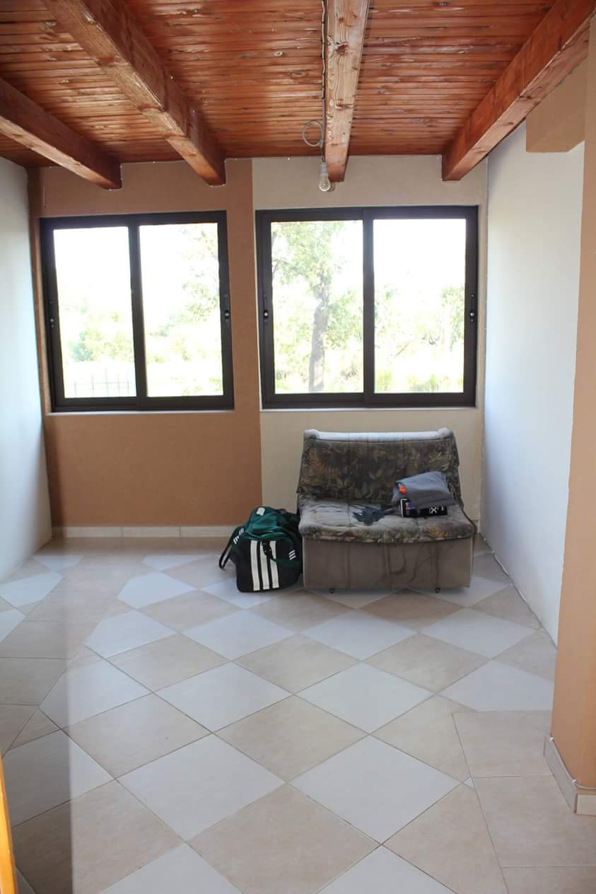 Living room in a house in Sutomore, Montenegro: a bright room with a wooden ceiling, tiled floor, and a view of the garden.