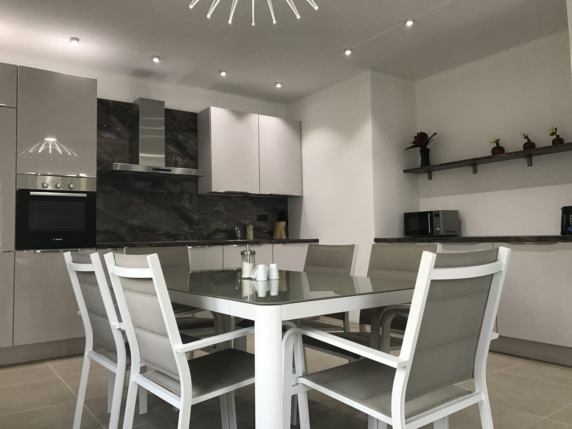 Modern kitchen with a glass dining table in a villa in Utjeha, Montenegro: stylish interior and built-in appliances.