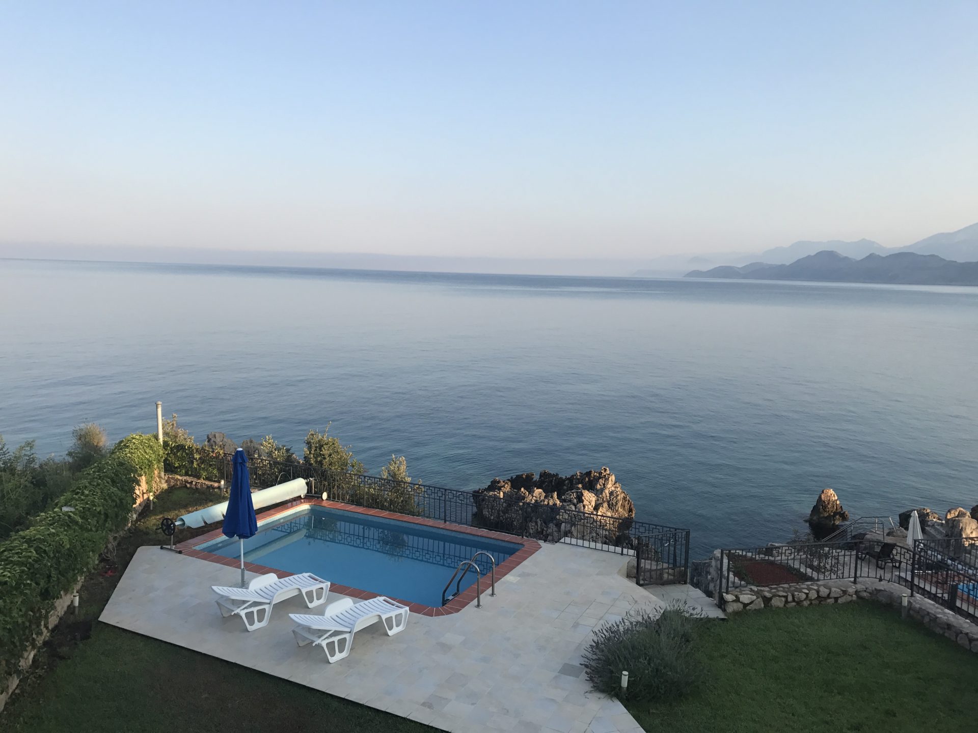 Open-air swimming pool with sun loungers and panoramic sea view at a villa in Utjeha, Montenegro.
