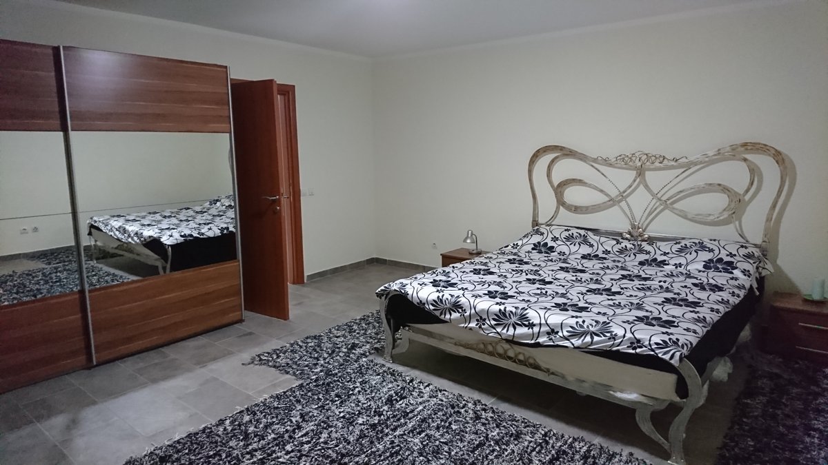 Bedroom in a villa in Utjeha, Montenegro: a double bed with a wrought-iron headboard, a mirrored wardrobe, and tiled flooring.
