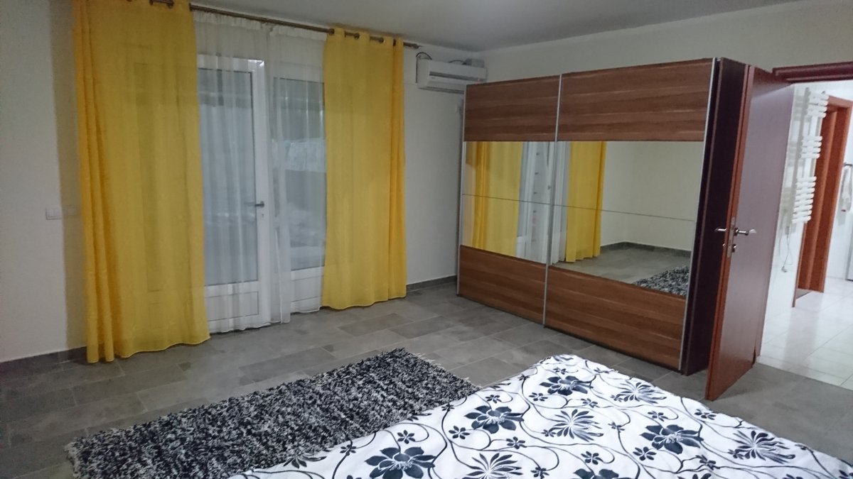 Bedroom in a villa in Utjeha, Montenegro: double bed, mirrored sliding wardrobe, yellow curtains, and access to the terrace.
