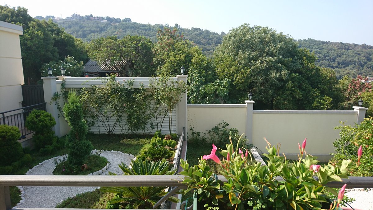 View from the villa balcony in Utjeha, Montenegro: a well-maintained landscaped garden with ornamental plants and mountains.