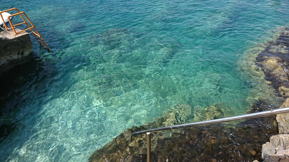 Private descent into the crystal-clear sea by the villa in Utjeha, Montenegro: rocky shore, staircase for entering the water.