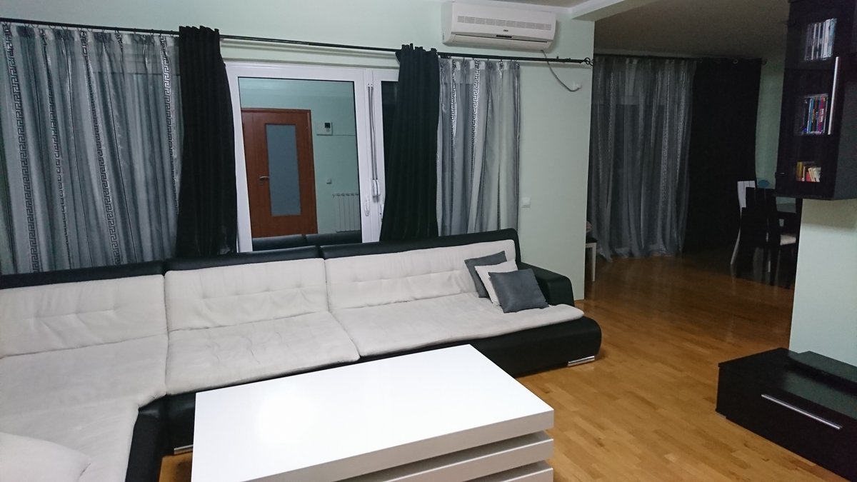 Living room with a black-and-white sofa and parquet flooring in a villa in Utjeha, Montenegro. Interior with air conditioning and panoramic windows.
