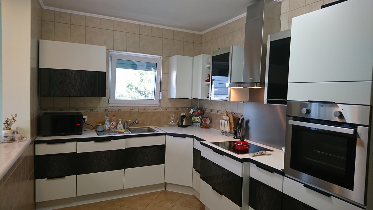 Modern black-and-white kitchen in a villa in Utjeha, Montenegro: built-in appliances, tile, and a bright interior.