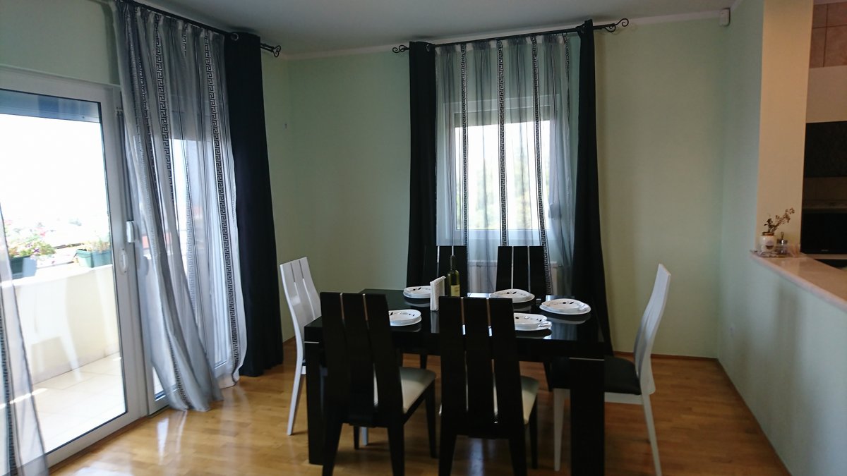 Living room with dining area in a villa in Utjeha, Montenegro: black table, contrasting chairs, and access to the terrace.
