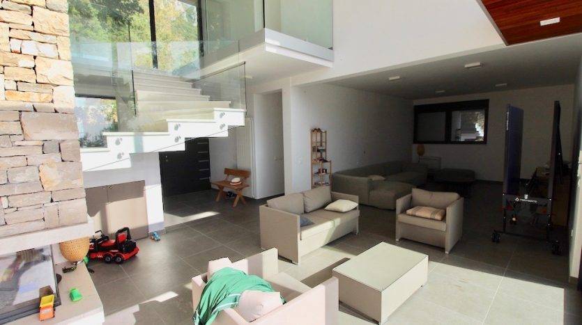 Modern living room in a villa in Herceg Novi, Montenegro: stone fireplace, glass staircase, and upholstered furniture.