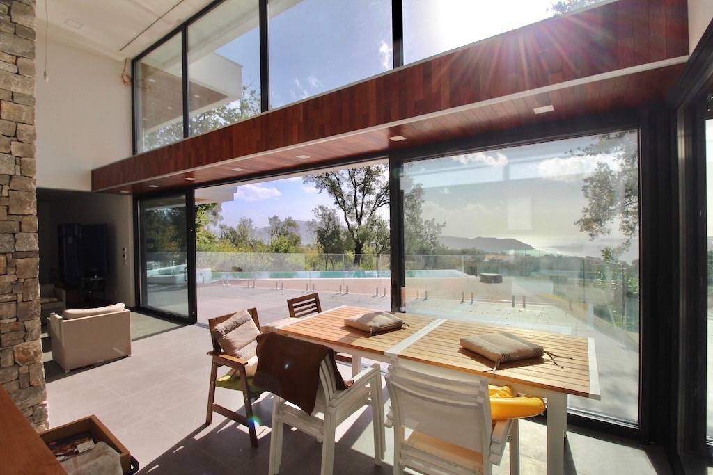 Villa living room in Herceg Novi, Montenegro: panoramic windows, view of the pool and sea, modern stone and wood finishes.