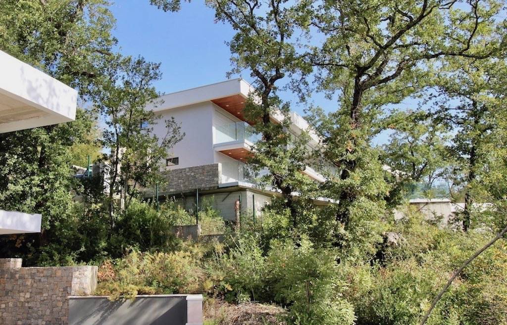 Modern villa in Herceg Novi, Montenegro: stone-clad facade, panoramic balconies, and a green garden.