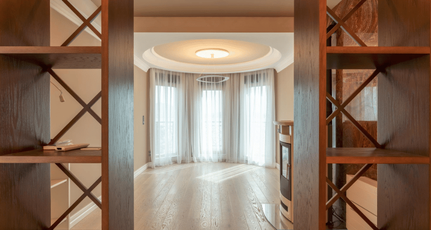 Living room with panoramic windows, a fireplace, and wooden shelving in a villa in Bijela, Montenegro.