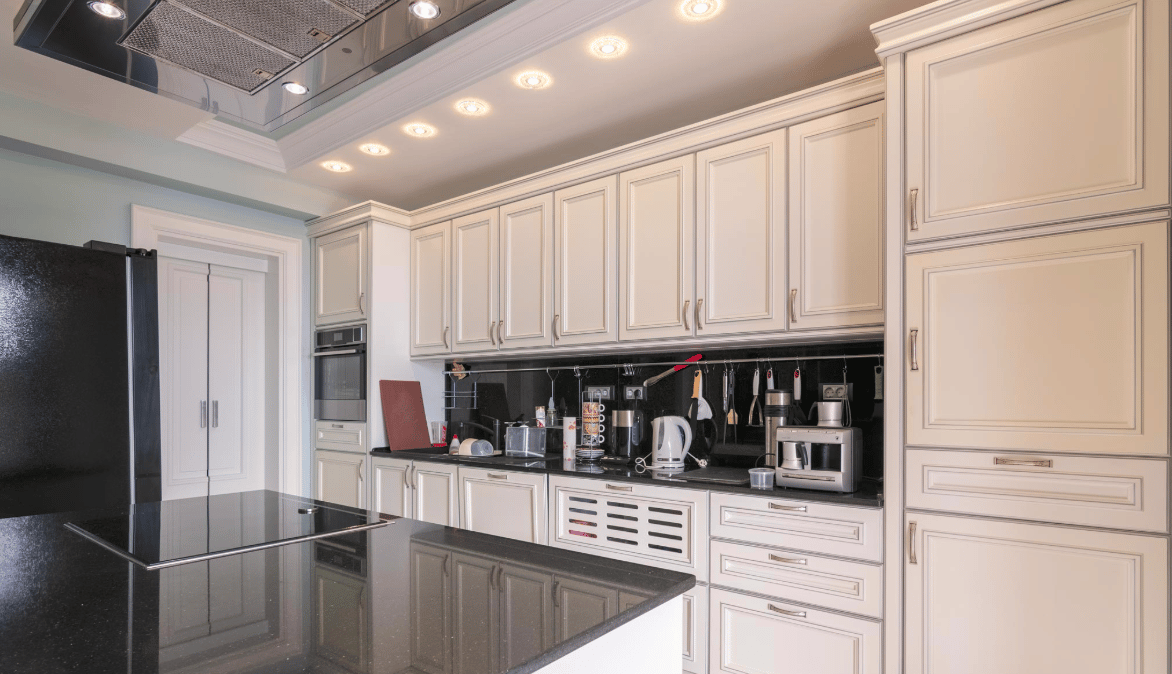 Modern kitchen with white fronts and a black countertop in a villa in Bijela, Montenegro. Built-in appliances and lighting.