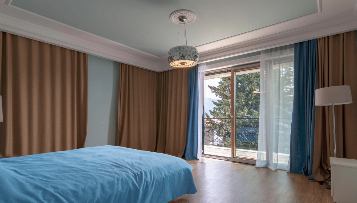Bedroom in a villa in Bijela, Montenegro: a double bed, panoramic windows with access to the balcony, and a view of greenery.