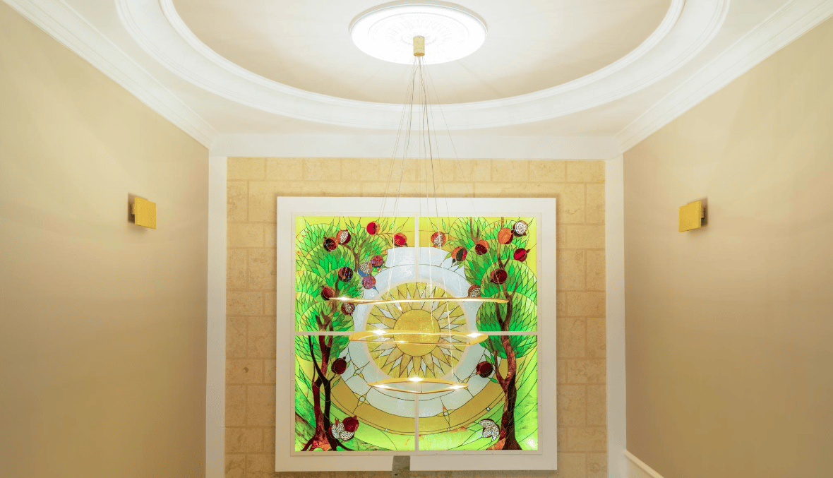 Interior of a villa in Bijela, Montenegro: a stained-glass panel with pomegranates, a modern chandelier, and classic wall finishing.