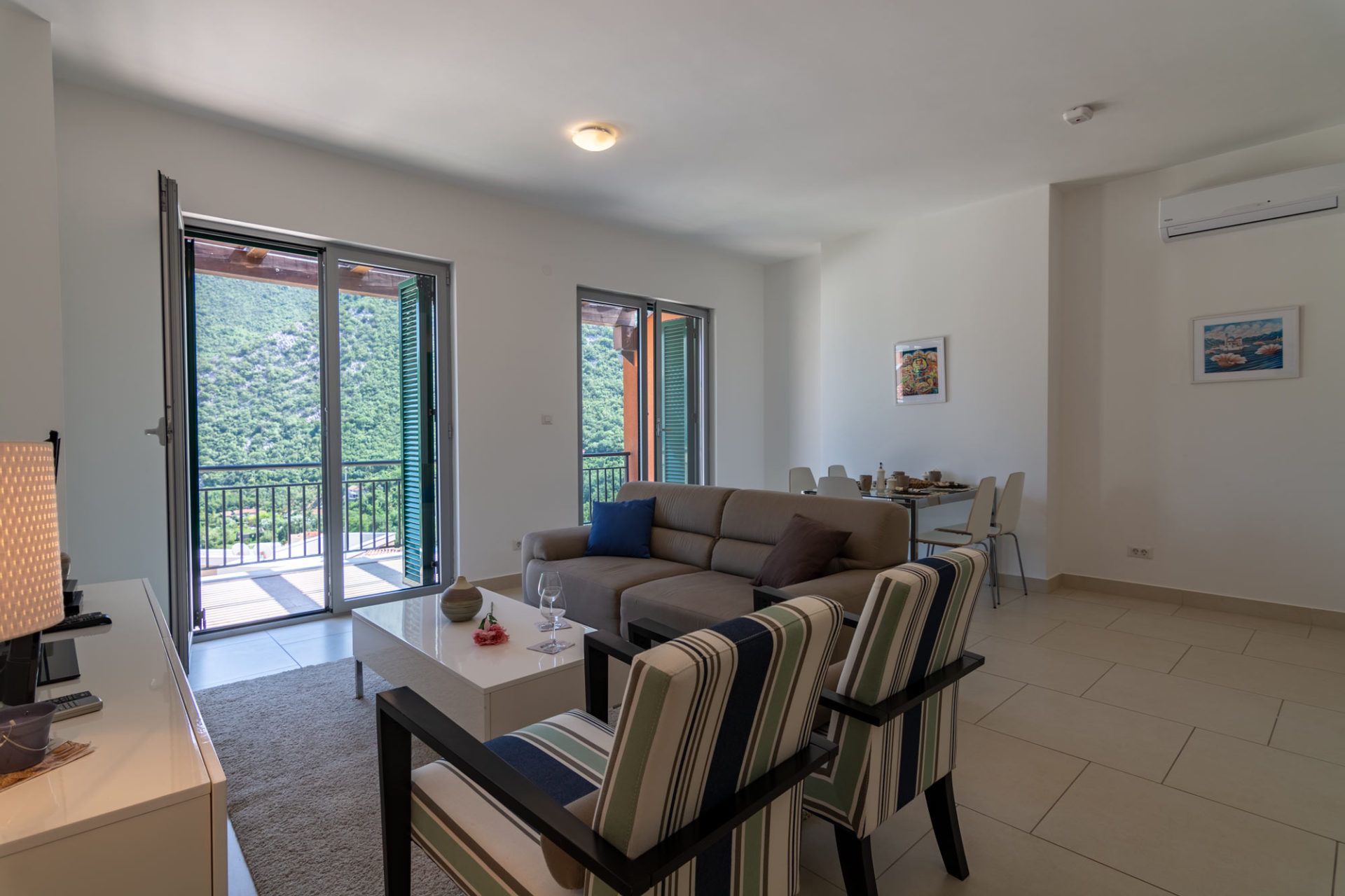 Living room in an apartment in Morinj, Montenegro: a bright room with soft seating, a dining area, and mountain views.