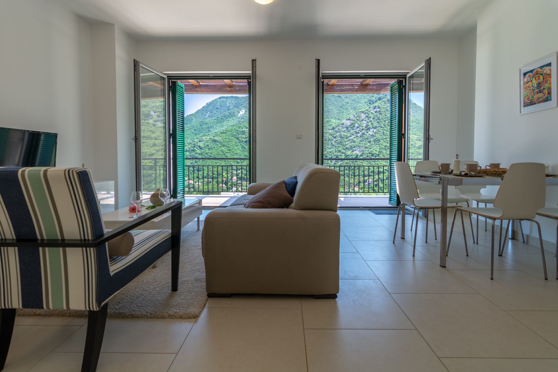 Living room in an apartment in Morinj, Montenegro: bright interior, soft furniture, and a terrace with a view of the green mountains.
