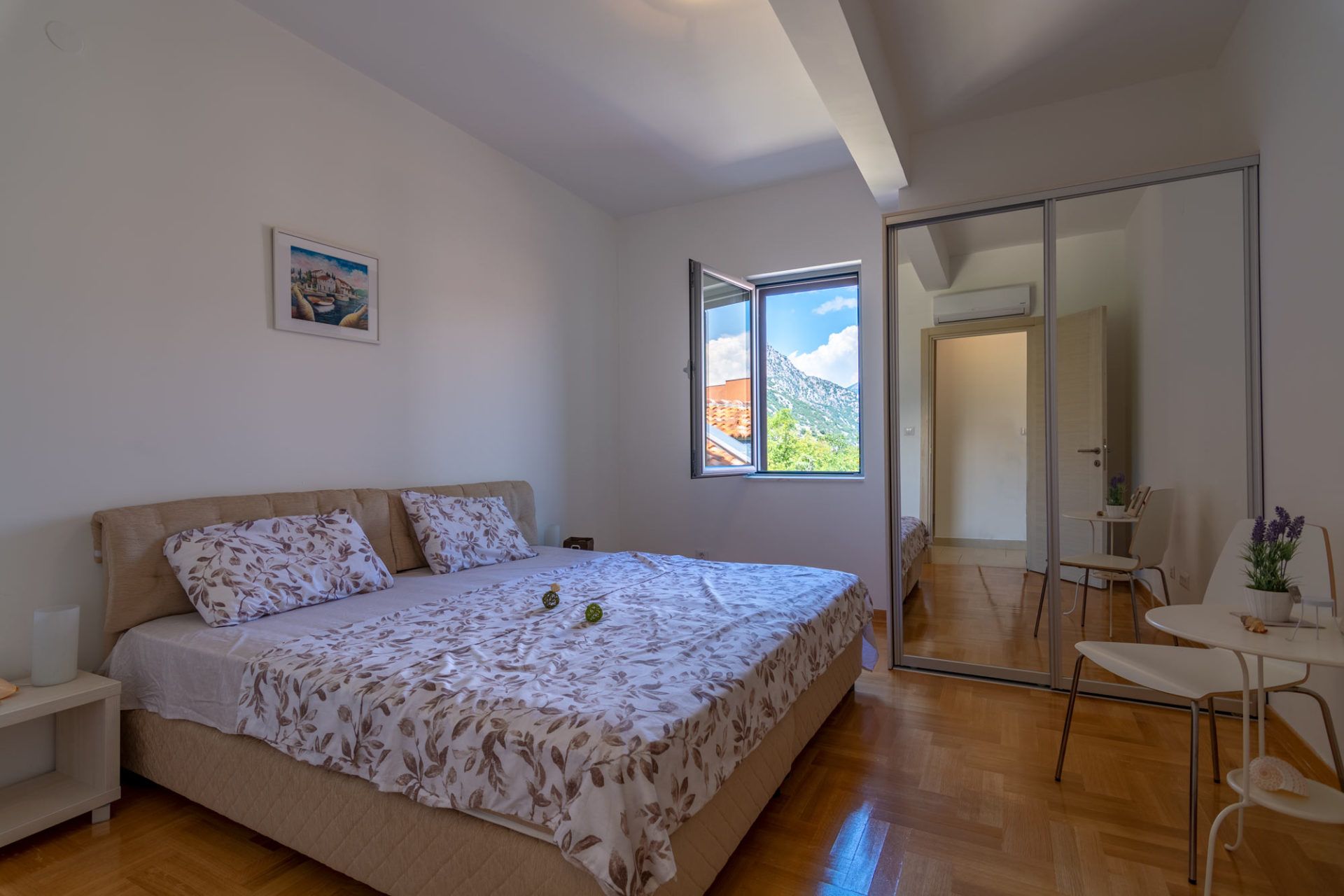 Bedroom in an apartment in Morinj, Montenegro: double bed, mirrored sliding wardrobe, and mountain view from the window.