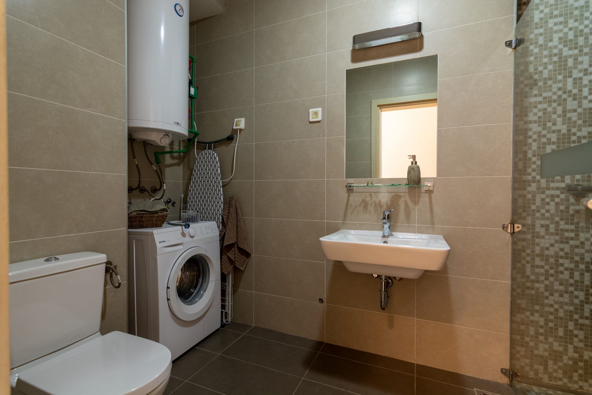 Bathroom in an apartment in Morinj, Montenegro: tiles, shower cabin, washing machine, and boiler.