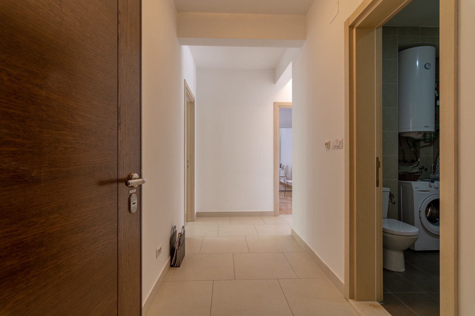 Bright hallway in an apartment, Morinj, Montenegro: tiled floor, interior doors, and entrance to the bathroom with a washing machine.