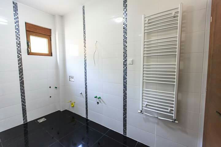 Modern bathroom with white tiles and a towel radiator in a house for sale in Šušanj, Montenegro.