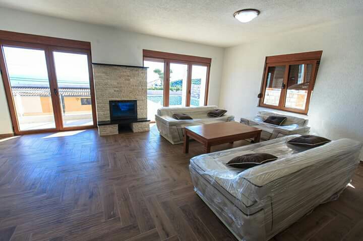Living room in a house in Shushan, Montenegro: a bright room with a fireplace, new furniture, and panoramic windows with a sea view.
