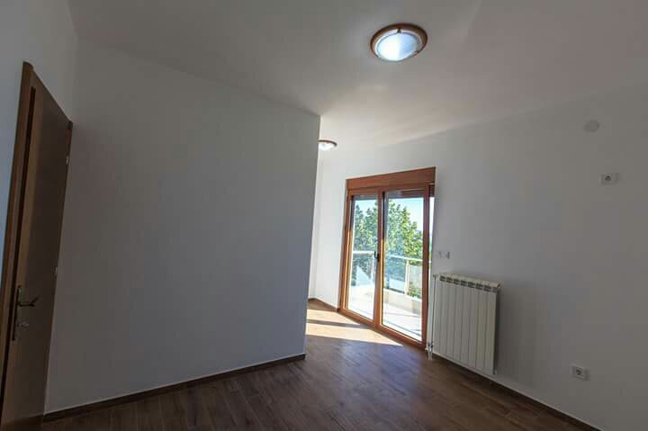Bright bedroom with access to the balcony in a house, Šušanj, Montenegro: laminate flooring, white walls, and a heating radiator.