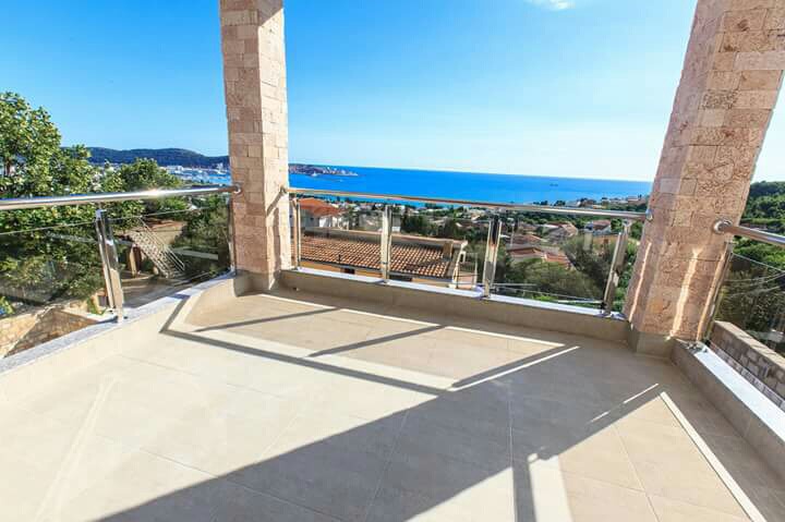 Spacious terrace with panoramic sea view in a house, Shushan, Montenegro: stone columns and glass railing.