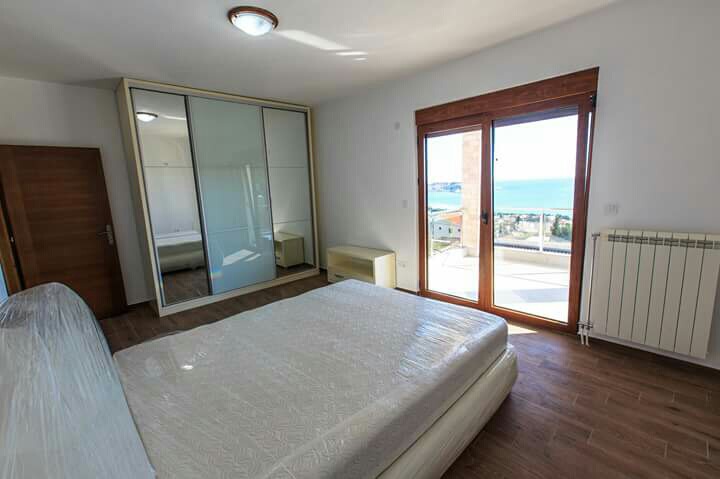 Bedroom with sea view in a house in Shushan, Montenegro: double bed, mirrored sliding wardrobe, and access to the terrace.