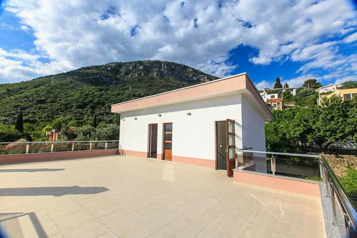 Spacious open terrace of a house in Šušanj, Montenegro, with mountain views and a modern glass and steel railing.