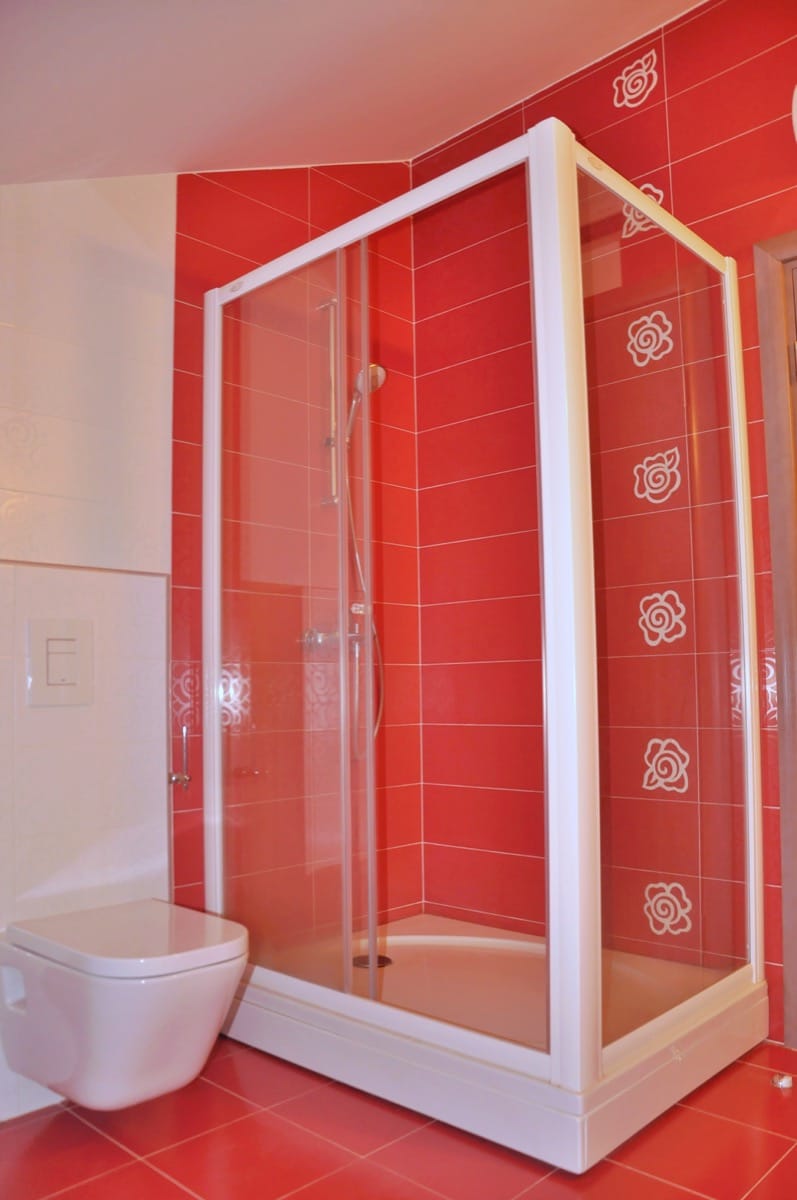 Bathroom with red tiles and a shower cabin in a villa in Đenovići, Montenegro. Modern plumbing fixtures.