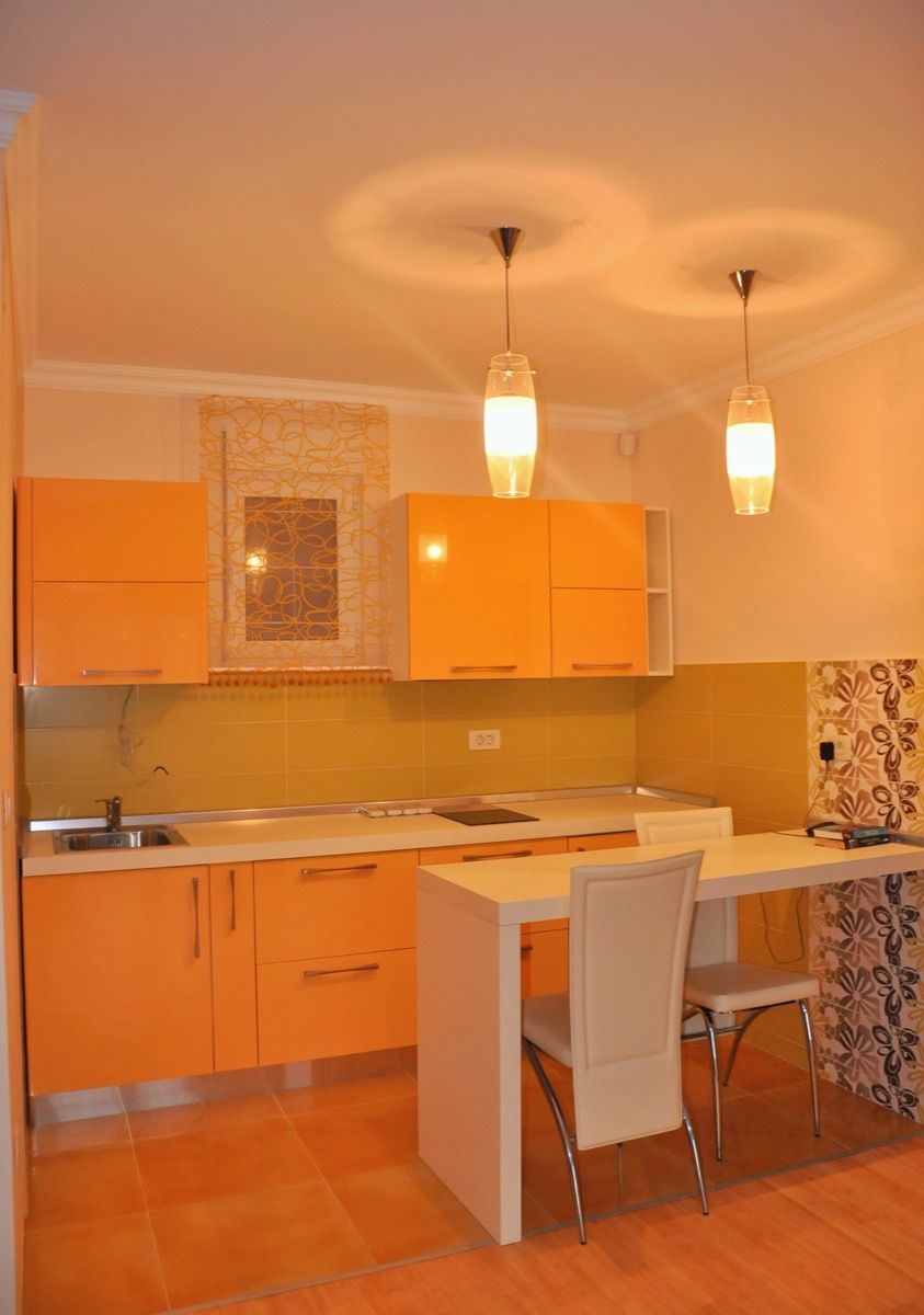 Modern orange kitchen with a bar counter in a villa in Đenovići, Montenegro: stylish interior and lighting.