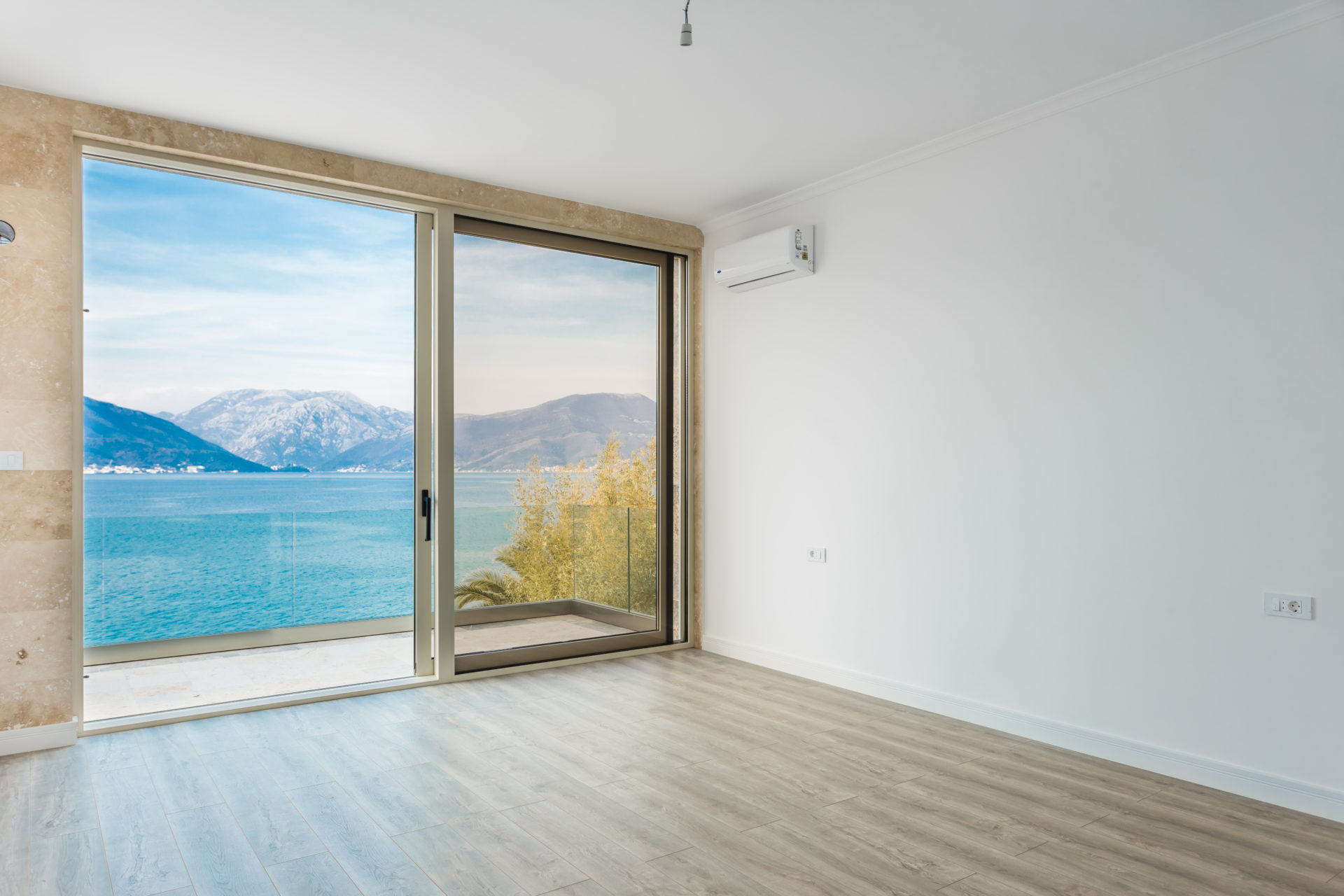 Bright living room with panoramic sea and mountain views in a villa, Krašići, Montenegro: laminate flooring, stone finishes, and air conditioning.