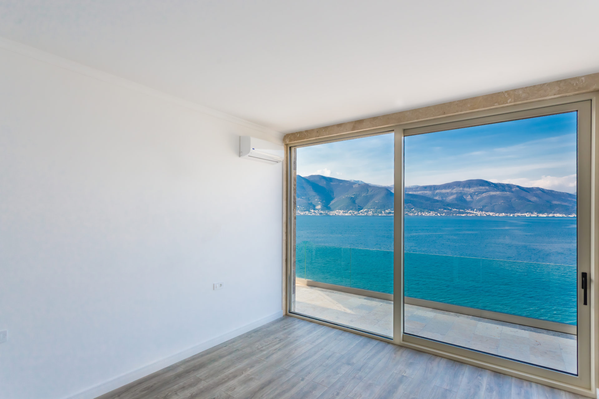 Bright living room with panoramic windows and a view of the sea and mountains in a villa in Krašići, Montenegro.