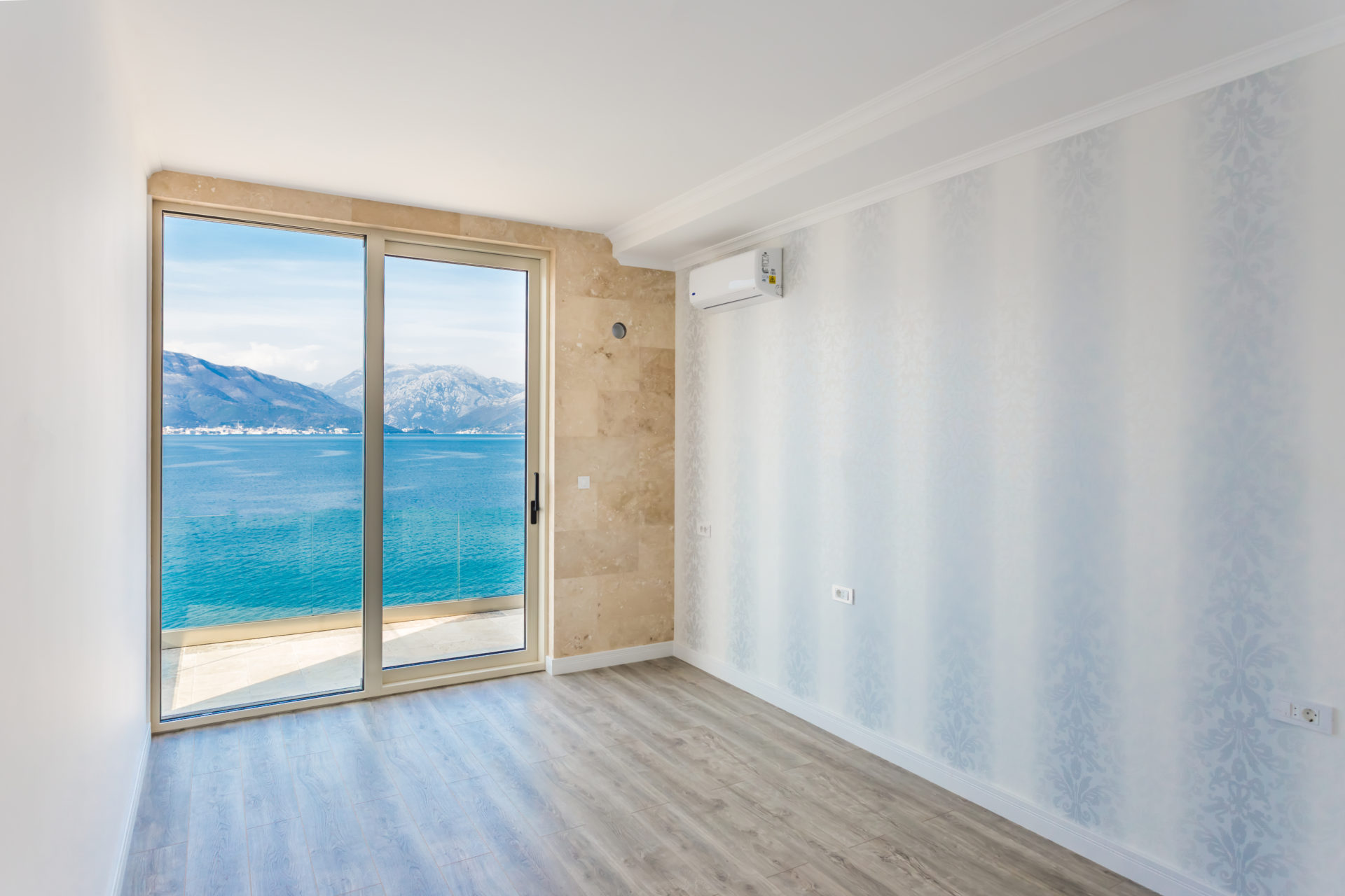 Living room with panoramic sea and mountain views in a villa, Krašići, Montenegro: bright finishes and access to the terrace.