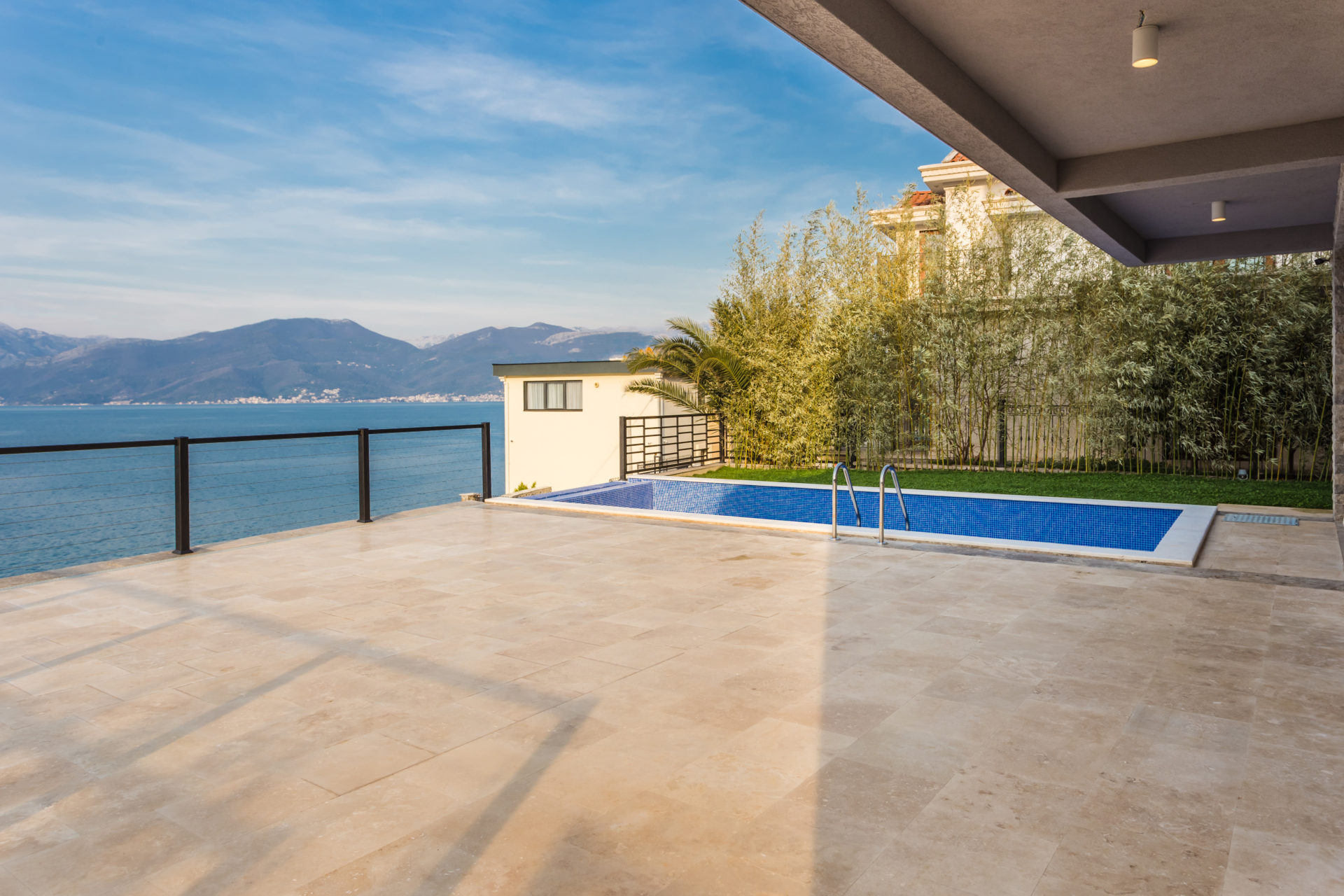 Villa terrace in Krašići, Montenegro: swimming pool with sea and mountain views, stone finishes, and landscape design.