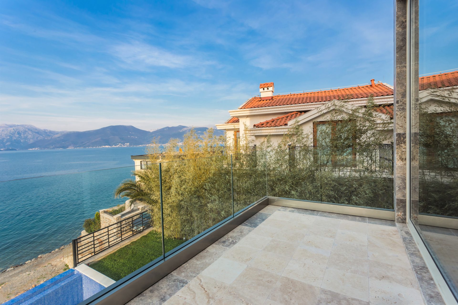 Villa terrace in Krašići, Montenegro: panoramic sea view, glass railing, and stone floor finish.