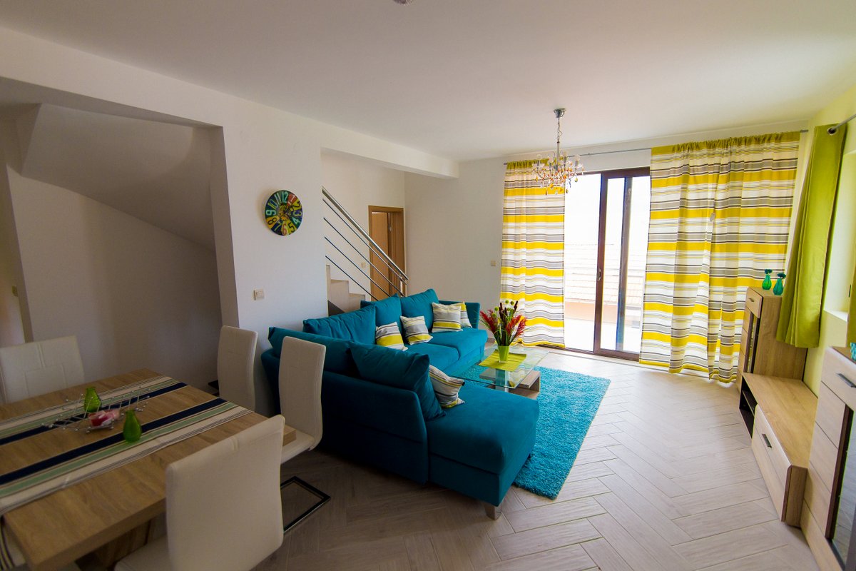 Living room with a blue sofa and dining area in a villa in Krašići, Montenegro: modern interior with access to the terrace.