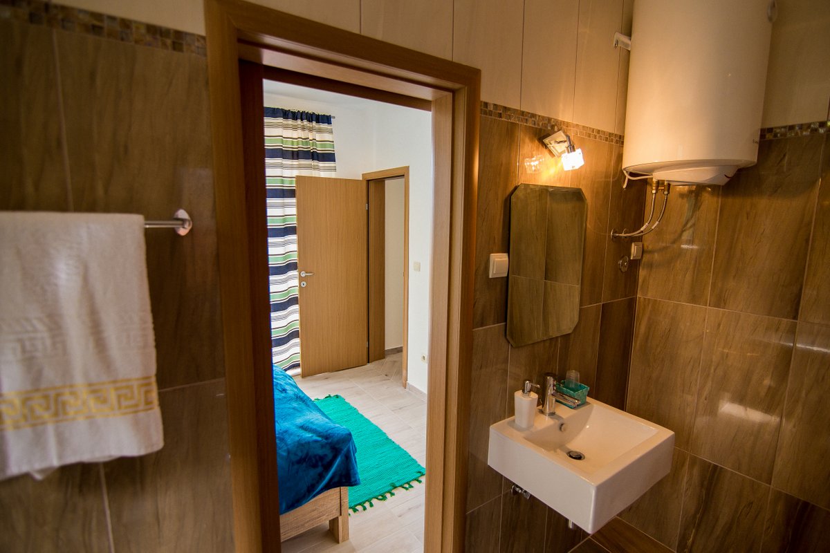 Bathroom with brown tiles and a view of the bedroom in a villa in Krašići, Montenegro: plumbing fixtures and a boiler.