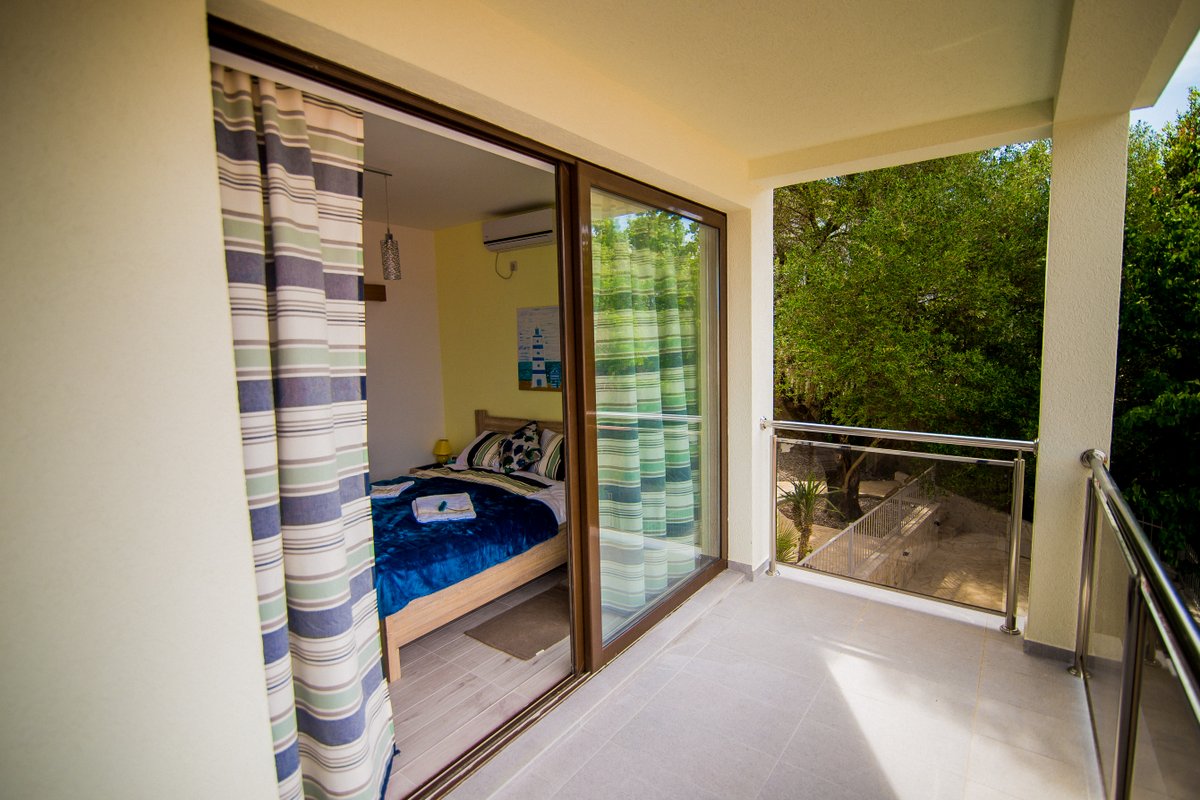 Balcony with panoramic views of greenery and a cozy bedroom in a villa in Krašići, Montenegro.
