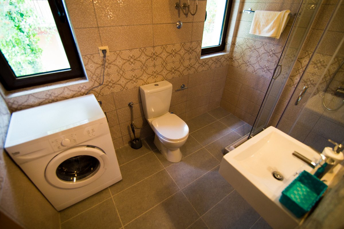 Bathroom with a shower cabin and washing machine in a villa in Krašići, Montenegro: modern tiled finish.