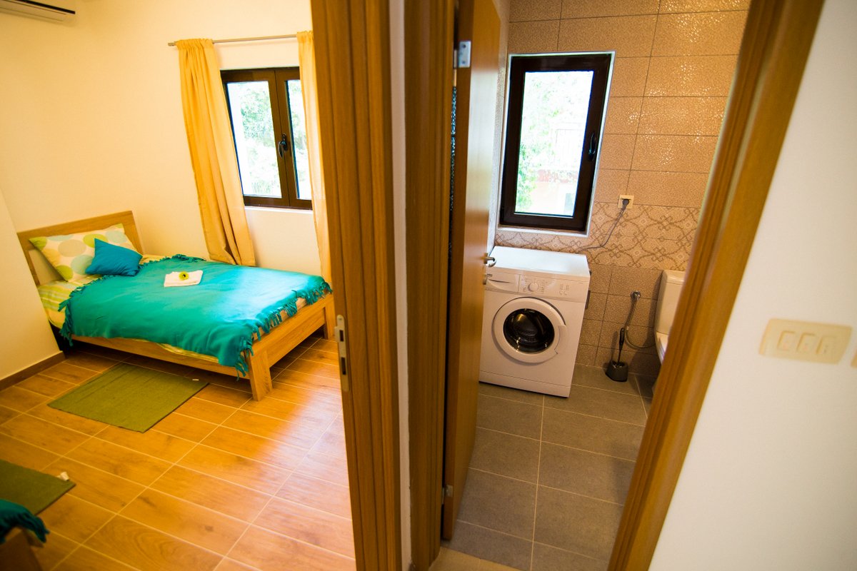 Bedroom with a bed and a bathroom with a washing machine in a villa in Krašići, Montenegro.