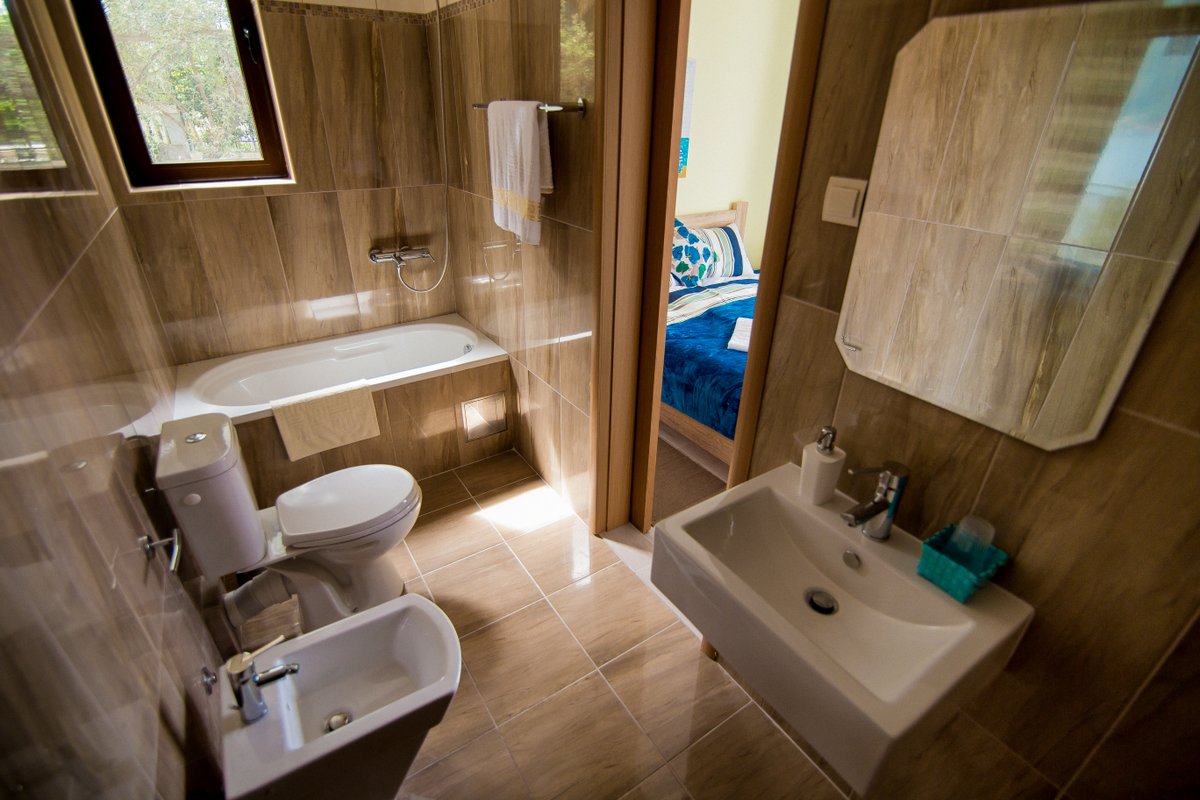 Bathroom with wood-look tiles, a bathtub, and a bidet in a villa in Krašići, Montenegro, with a view of the bedroom.