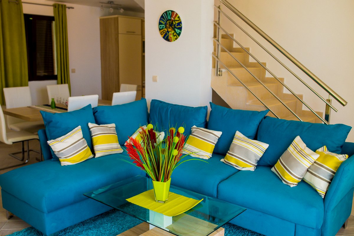 Living room with a blue sofa and staircase in a villa in Krašići, Montenegro: modern interior with a dining area.