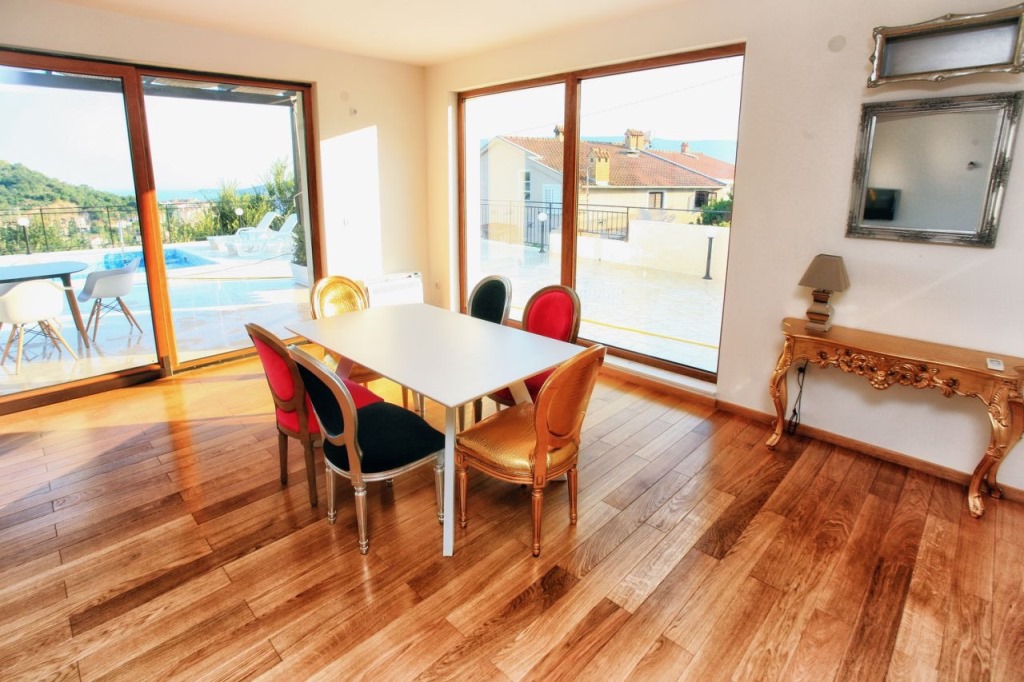 Living room with dining area and panoramic windows in a villa in Herceg Novi, Montenegro, view of the pool and the sea.