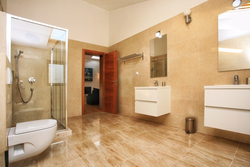 Modern bathroom with a shower cabin in a villa in Herceg Novi, Montenegro: white furniture and beige tiles.